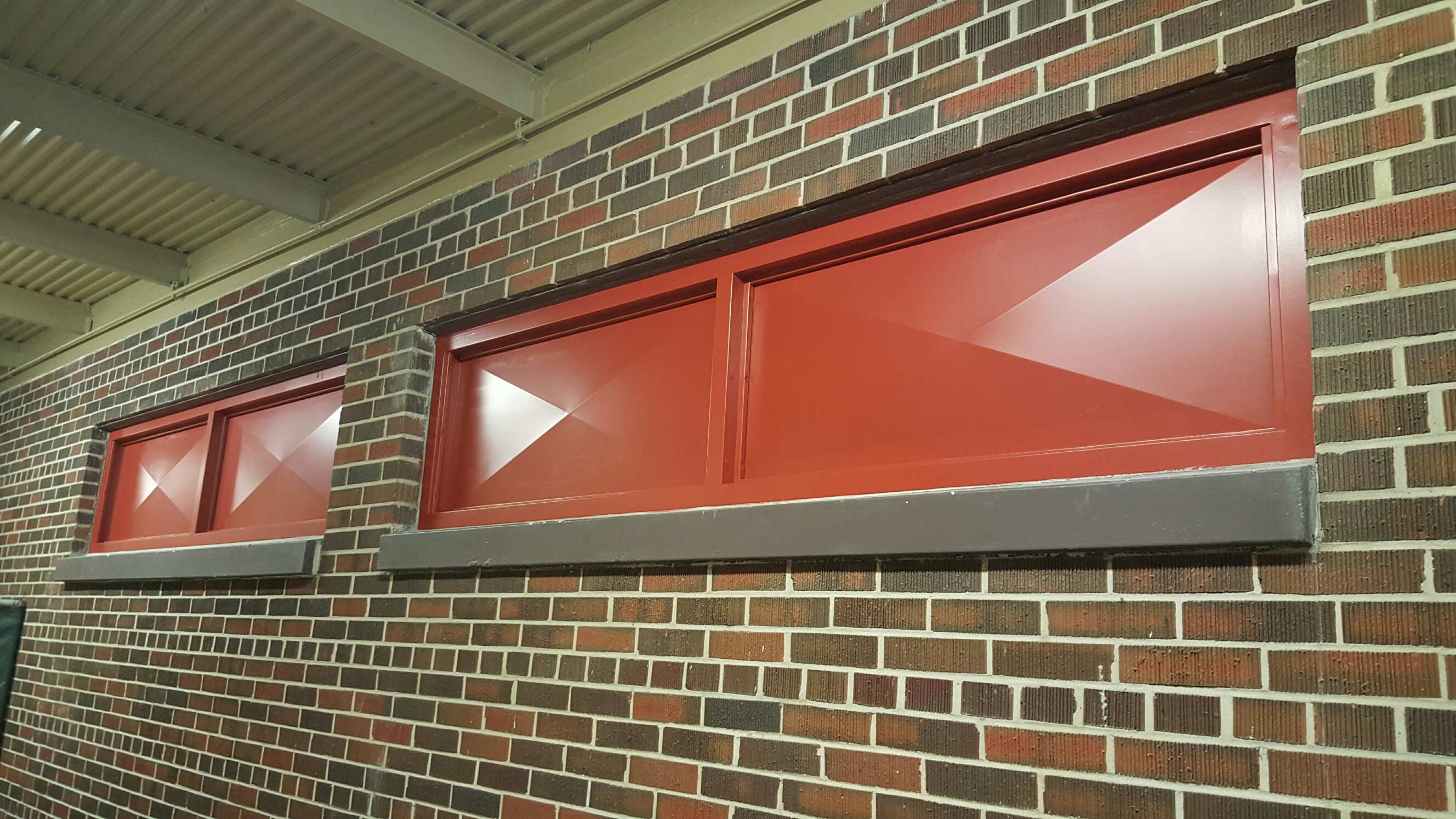 Red hollow metal window frames in a brick wall